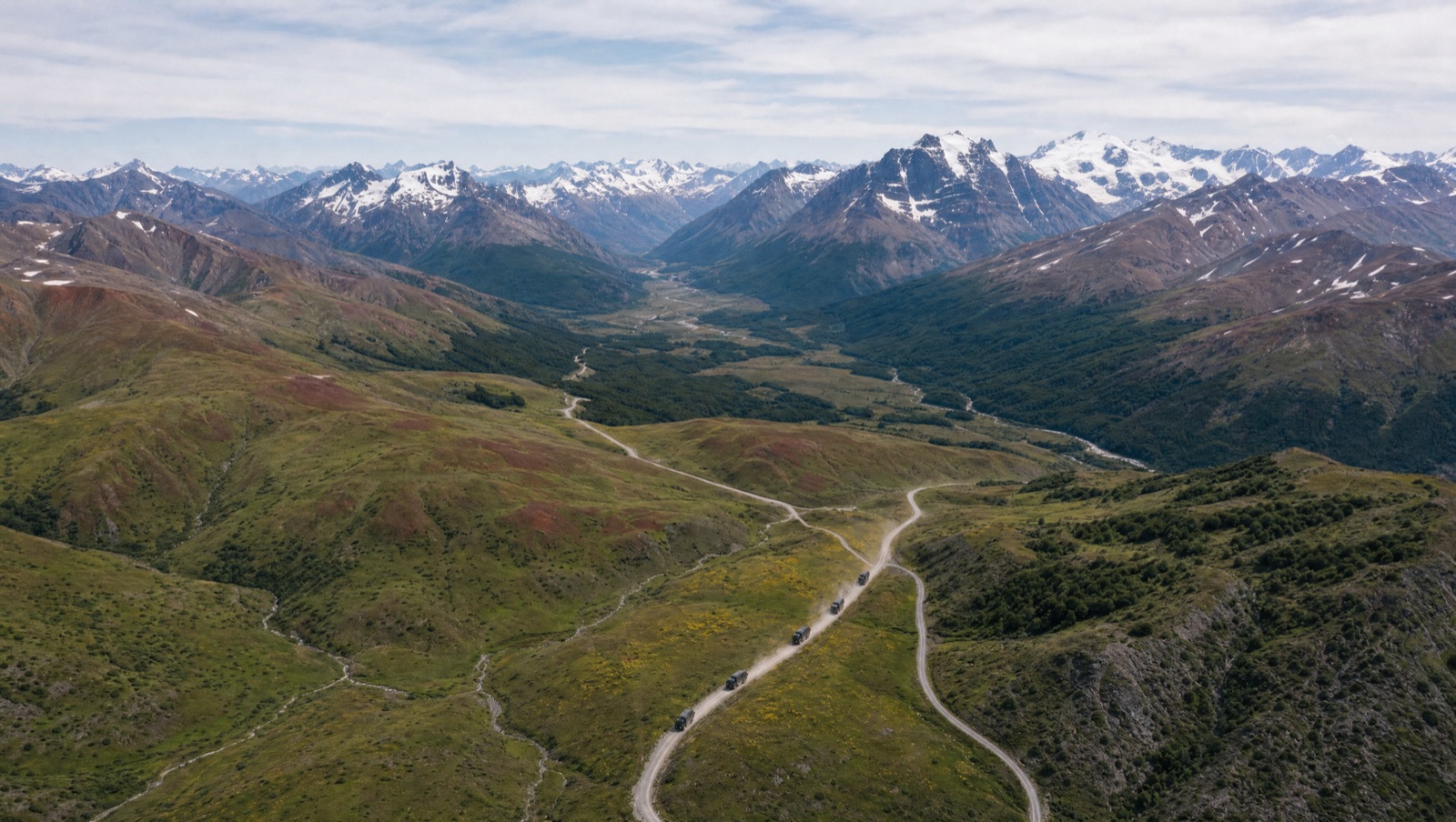 Convoy of expedition trucks on a mountain valley road